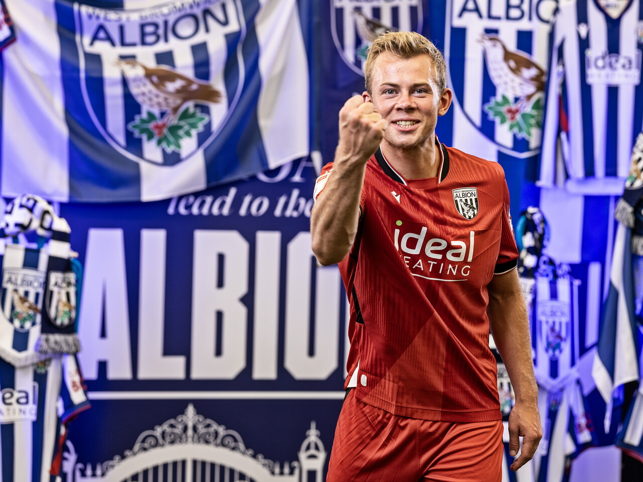 Aune Heggebø in the red away kit celebrating towards camera while stood in front of an Albion back drop with plenty of WBA branding