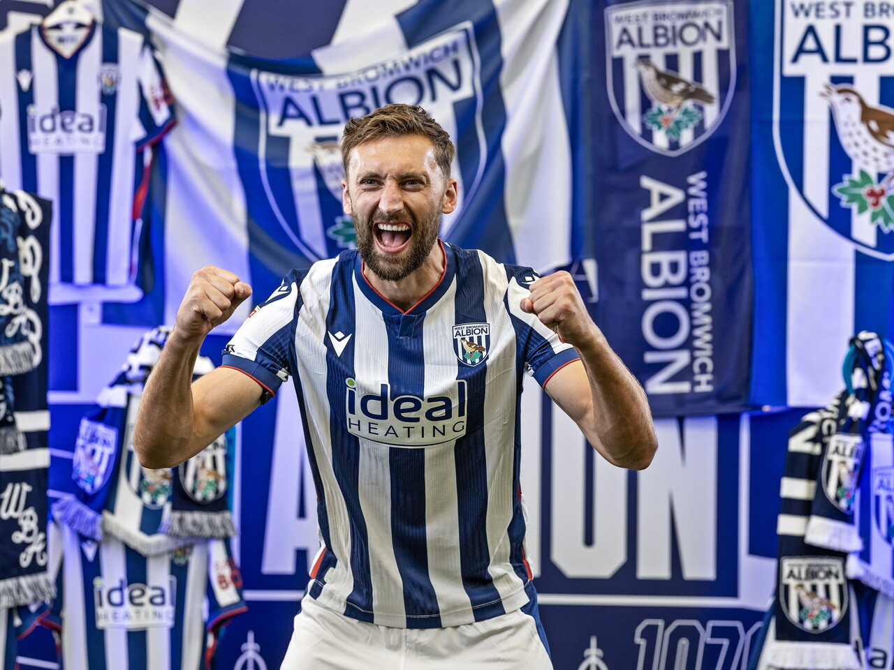 Nat Phillips in the home kit celebrating towards the camera while stood in front of an Albion back drop with plenty of WBA branding