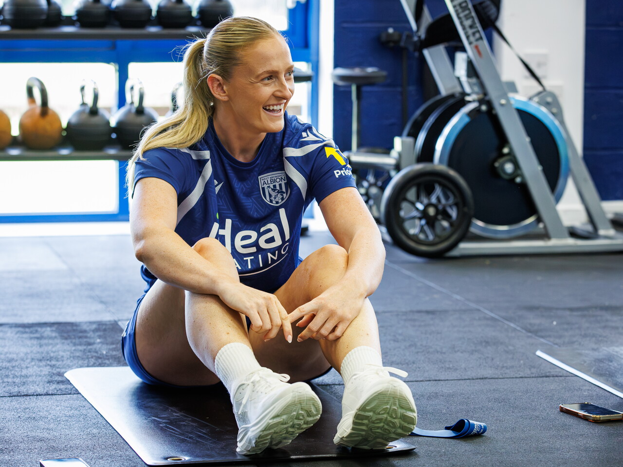 Zoe Creaney sat on a mat in the gym smiling and laughing 
