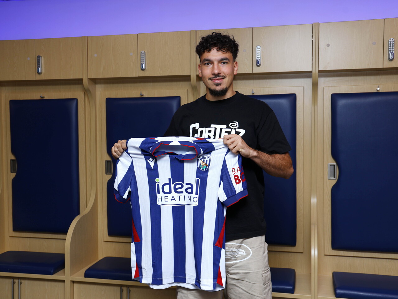 Nolan Galves smiling at the camera while holding up the home kit 