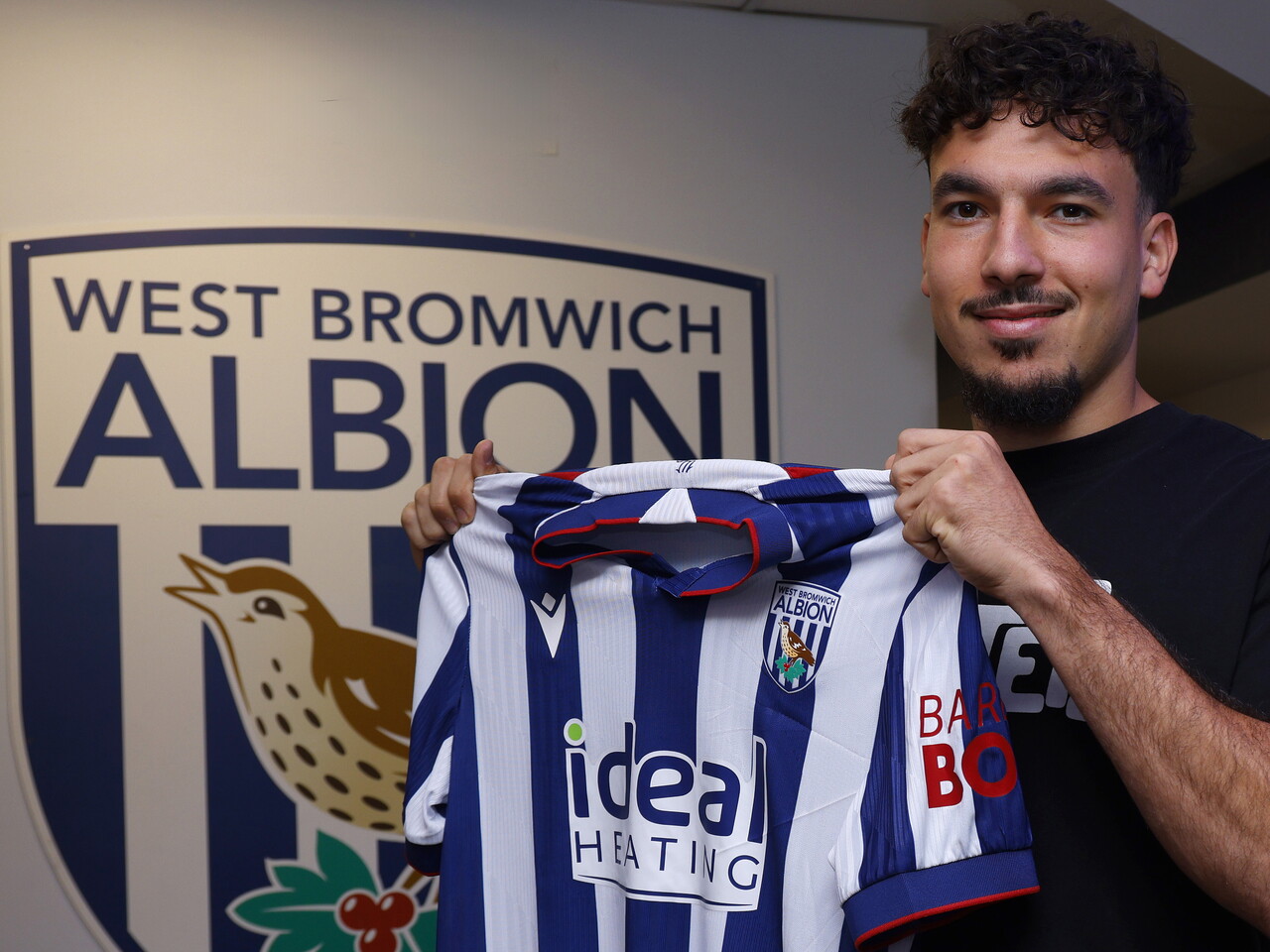 Nolan Galves smiling at the camera while holding up the home kit 