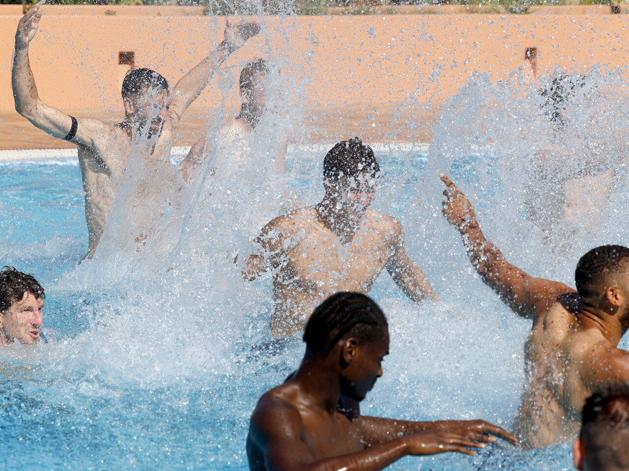 Several WBA players playing with a ball and splashing water in a swimming pool