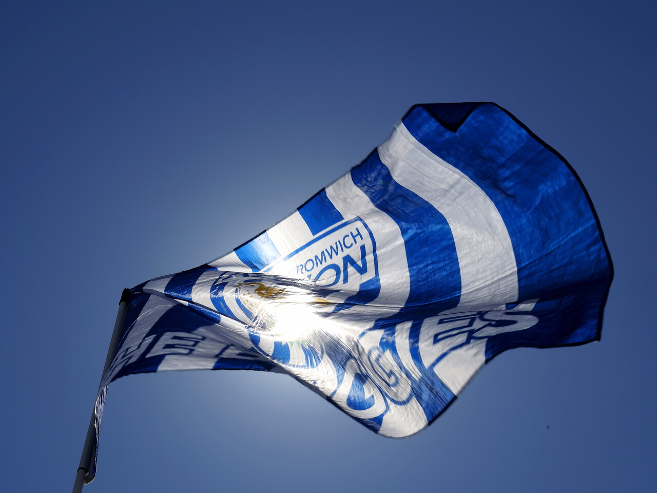 A WBA flag waving in the win in front of the sun