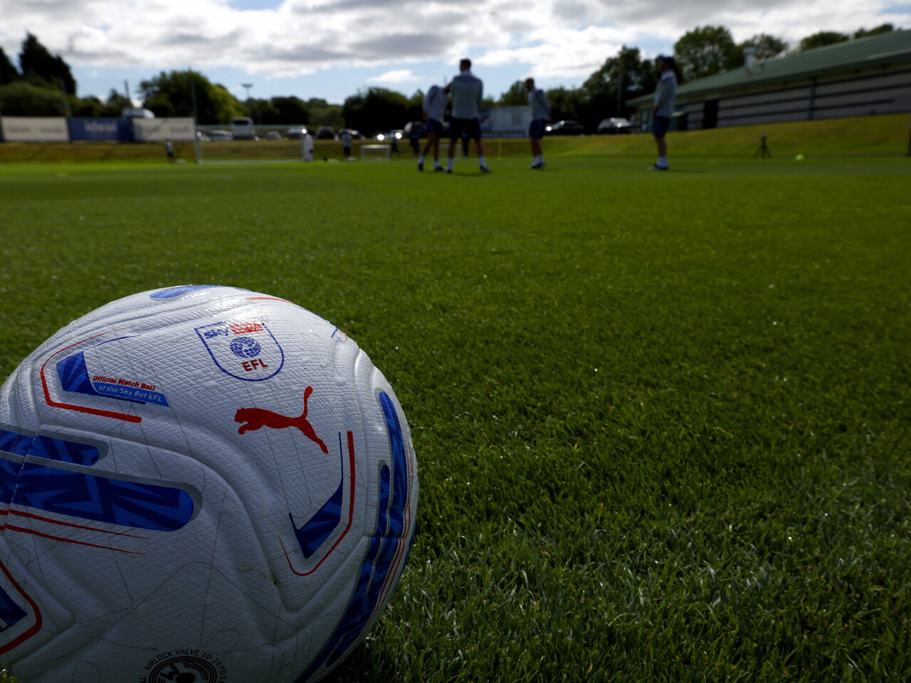A football on the training pitch with a session going on in the background 