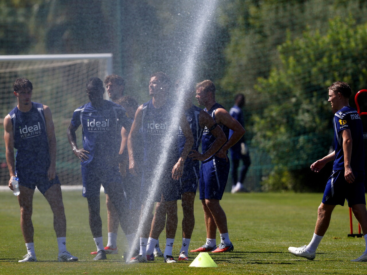 Several WBA players stood behind a sprinkler during a training session 