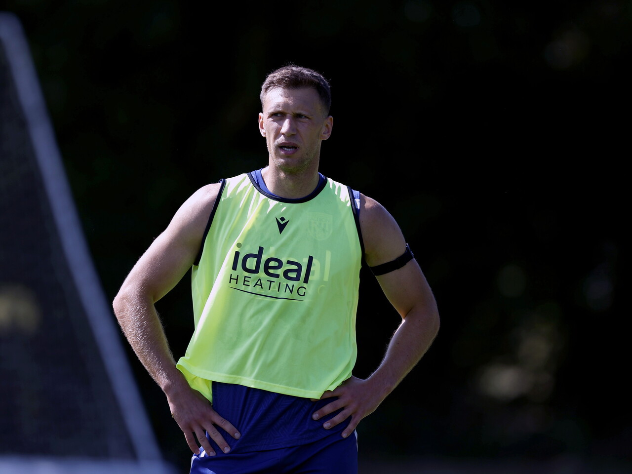 Krystian Bielik with his hands on his hips while wearing a green training bib 