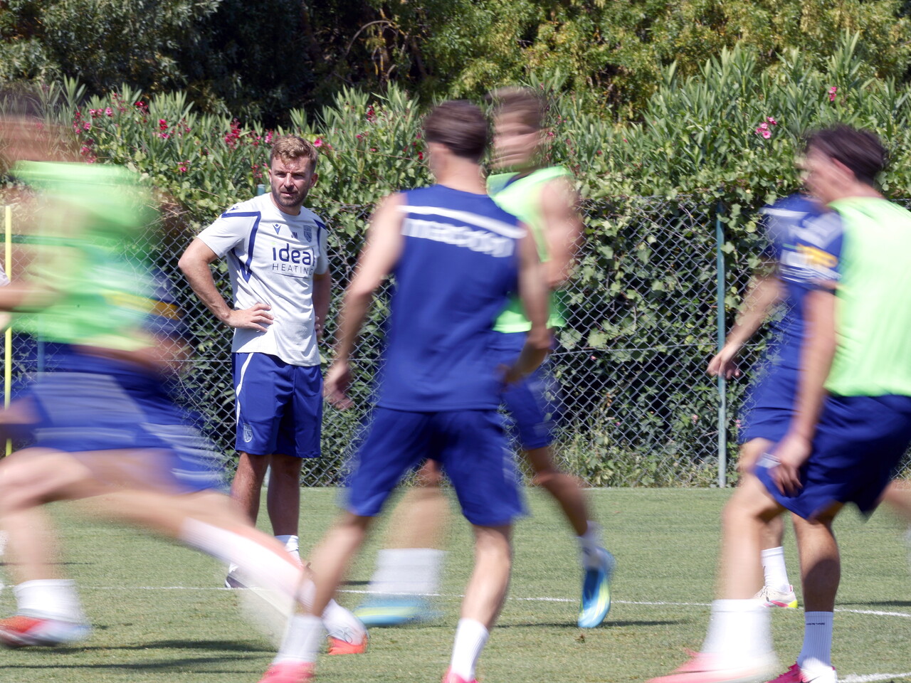 James Morrison watching training with several players in action in front of him