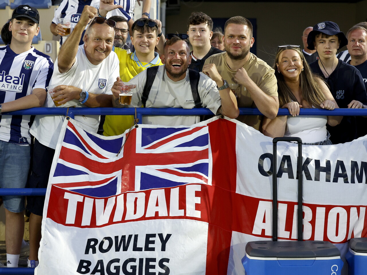 Several WBA fans pose for a photo in front of a WBA flag