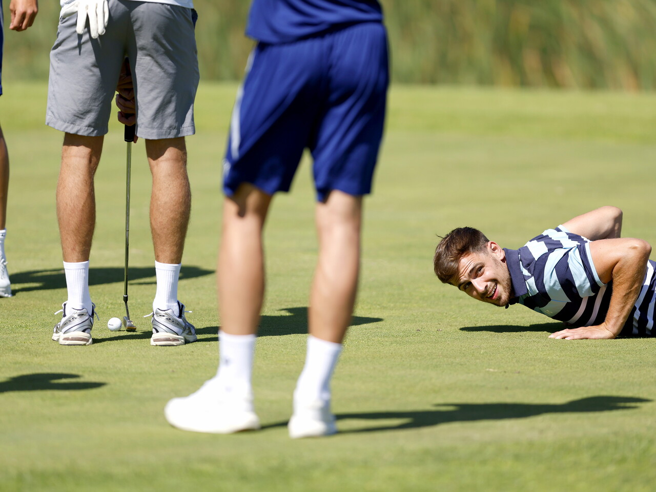 Jayson Molumby lying on the floor during a round of golf