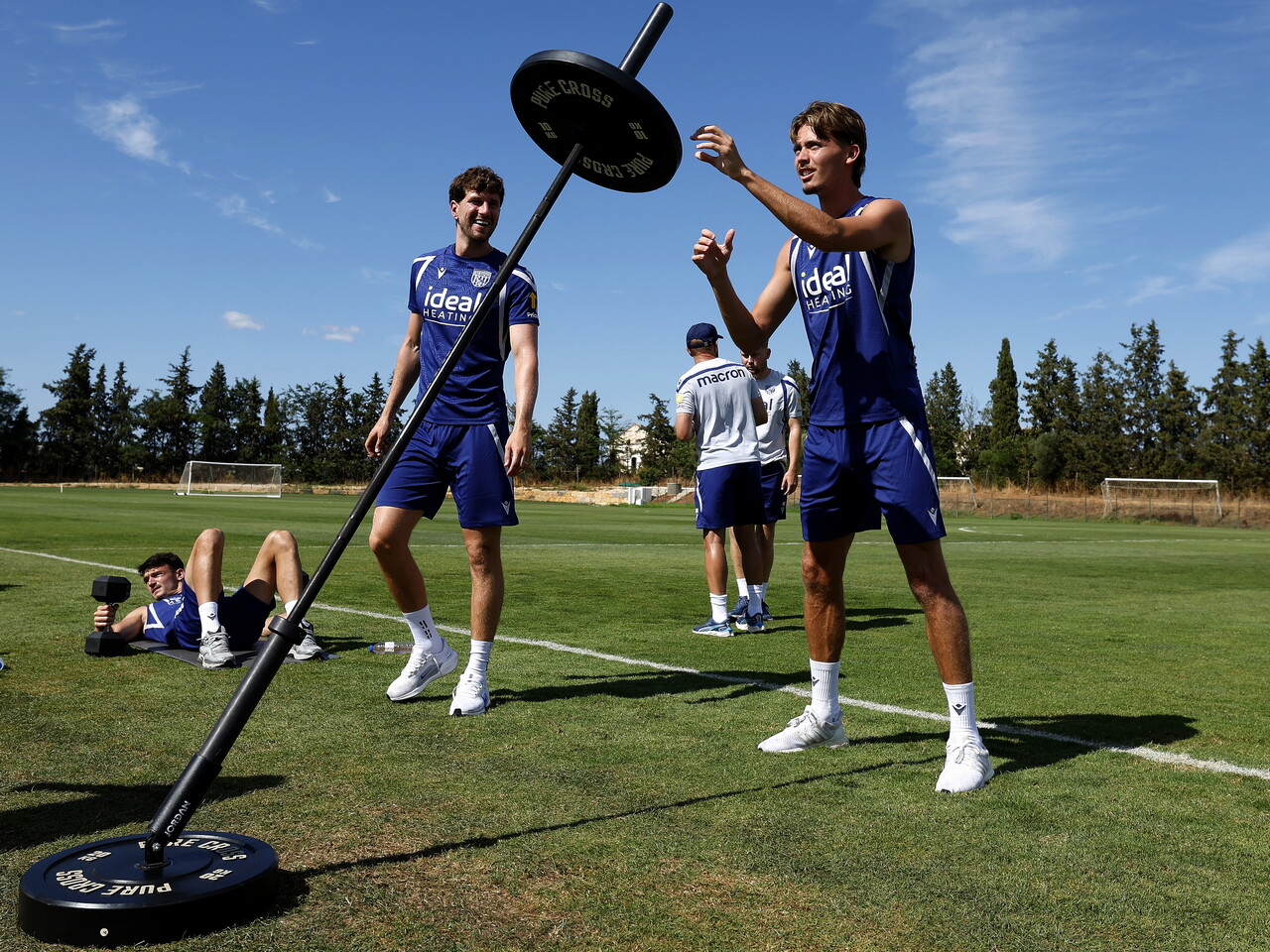 Isaac Price using gym weights outside on the training pitch while stood with Chris Mepham