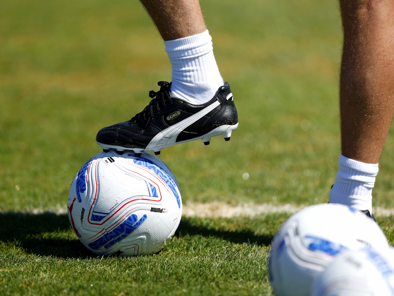A coach with his boot on the ball on the training pitch 