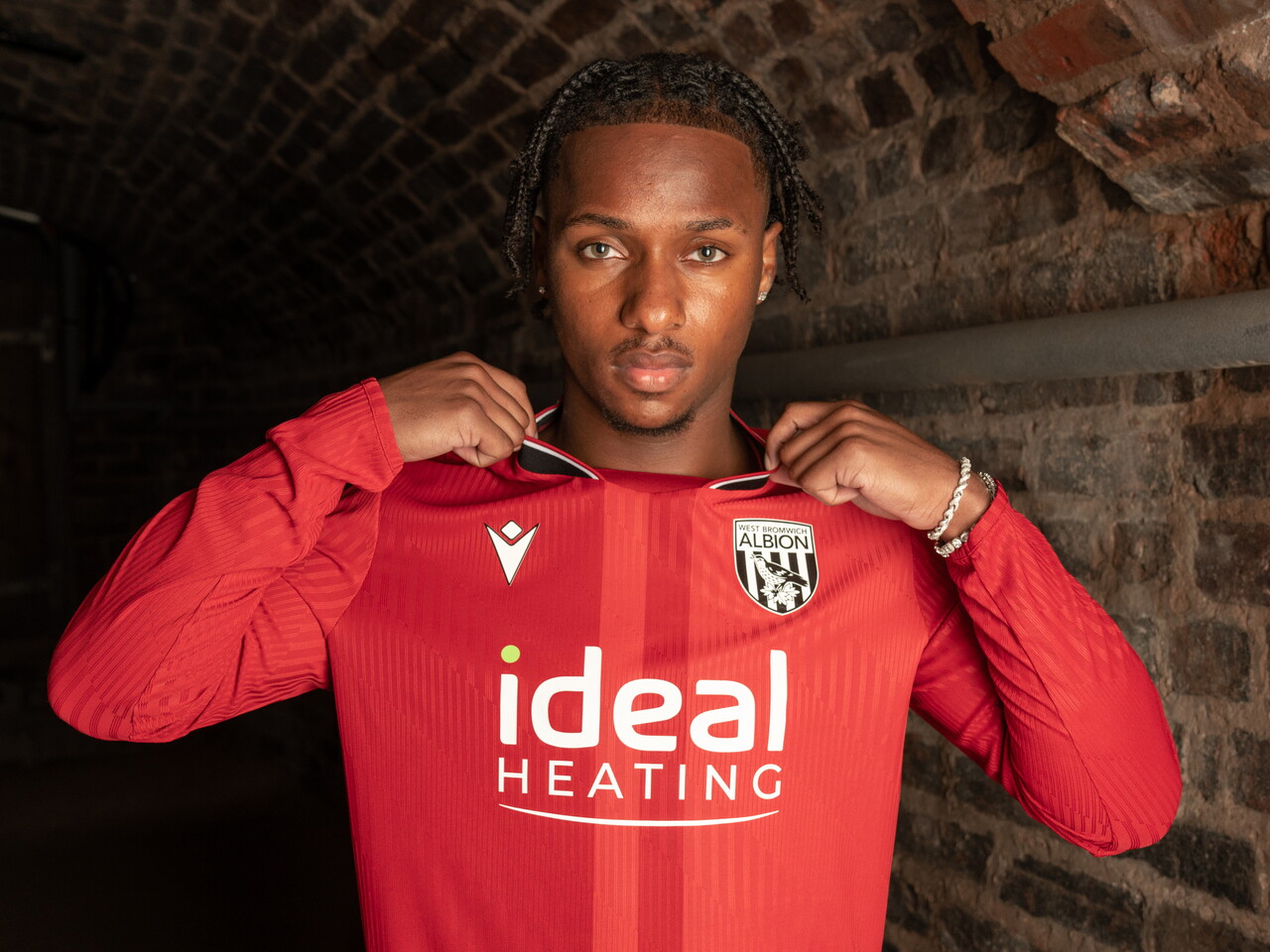 A model posing for a photo in the red away kit 