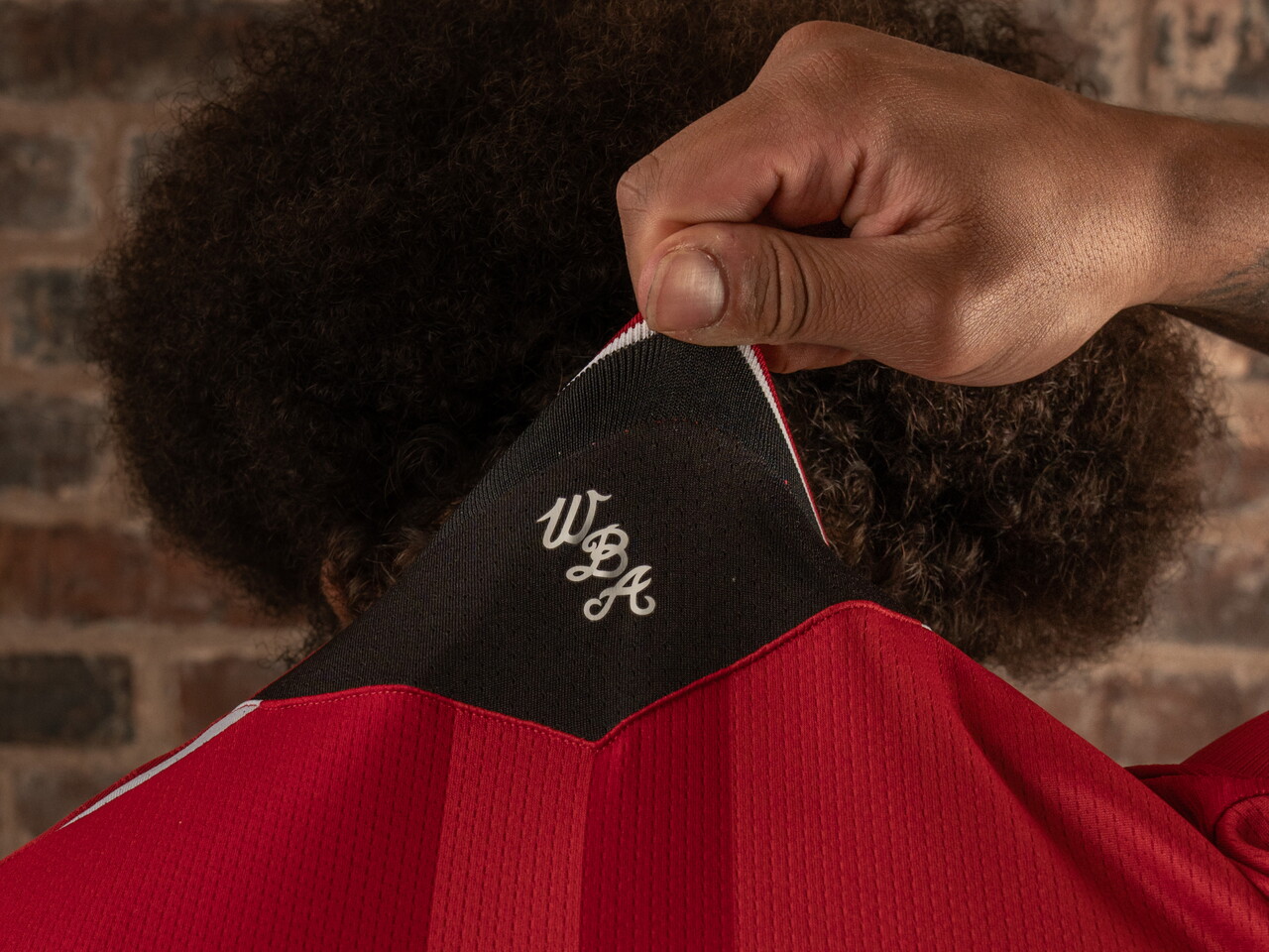 a model holding up the back collar of the shirt
