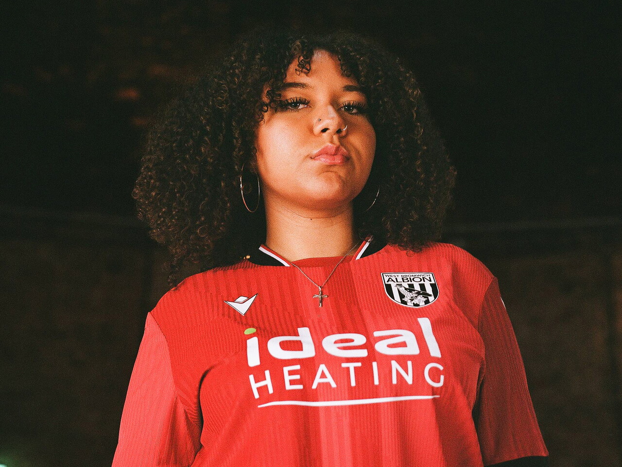 a model posing for a photo in the red away kit 