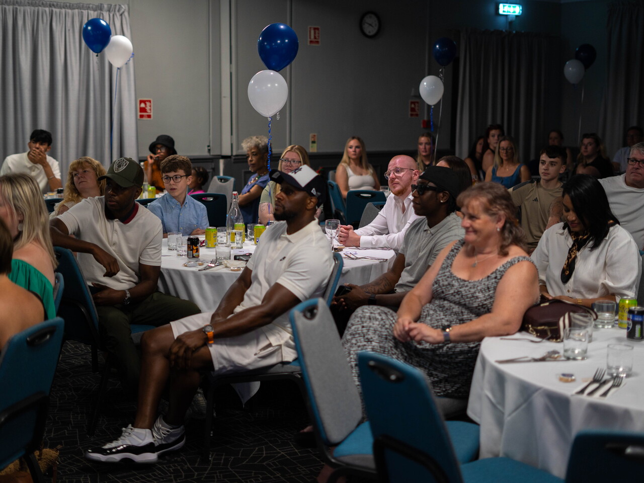 Guests seated at their tables, listening intensely.