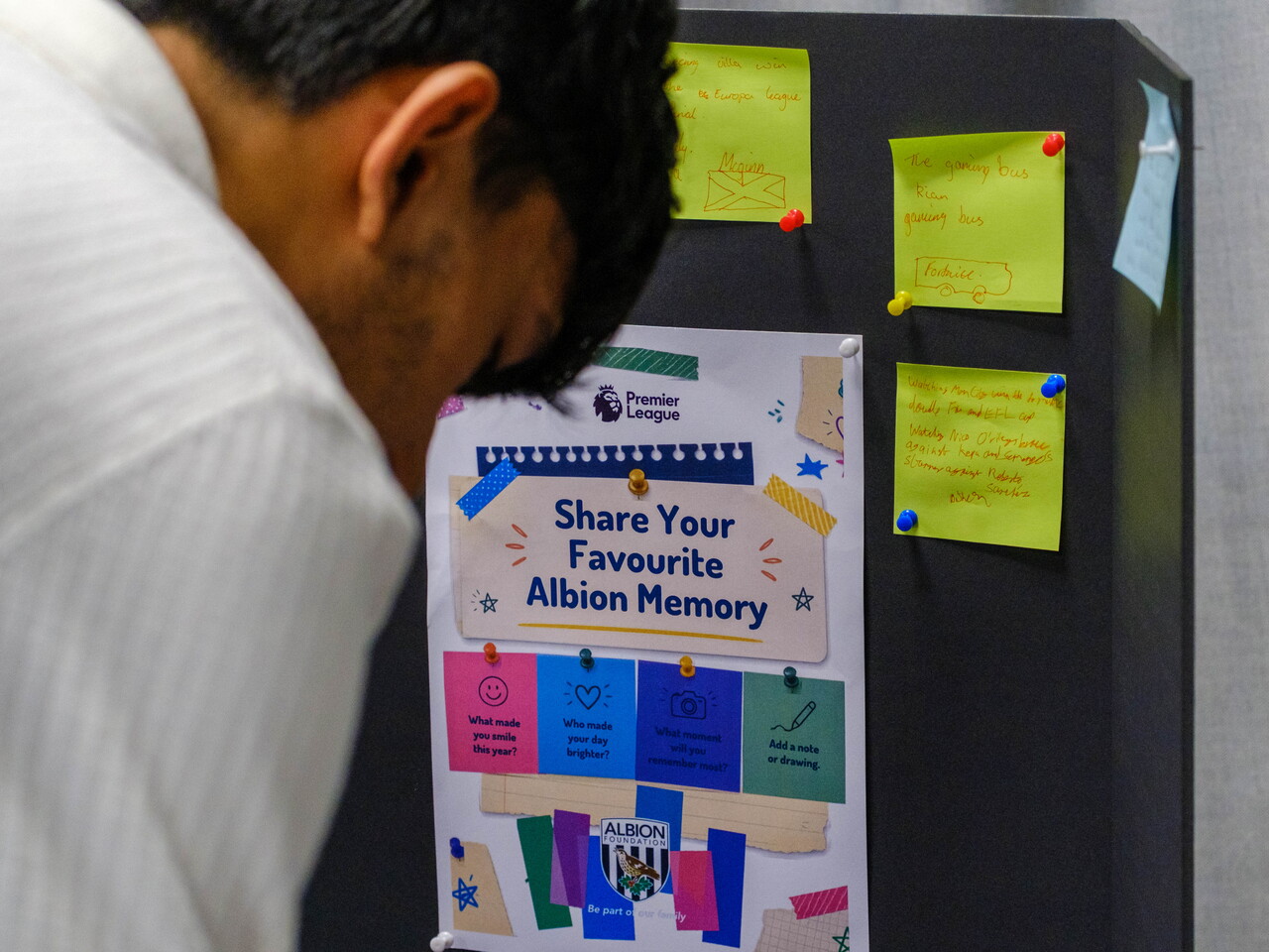 Participant writing on a post-it to pin on Foundation Memories board.