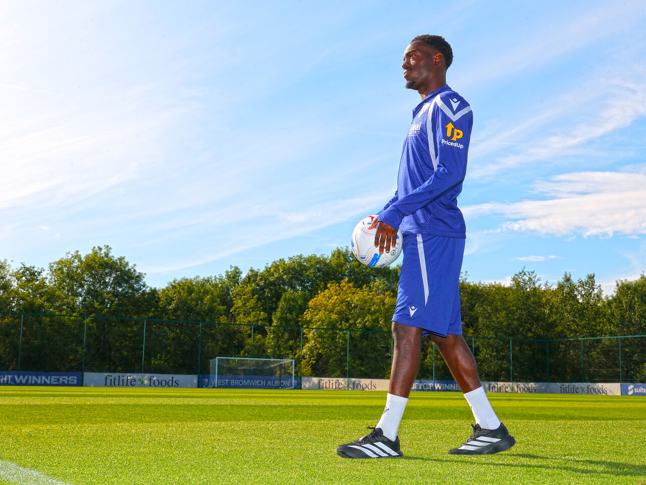 Rabby Nzingoula walks on the training pitch with a ball in his arms