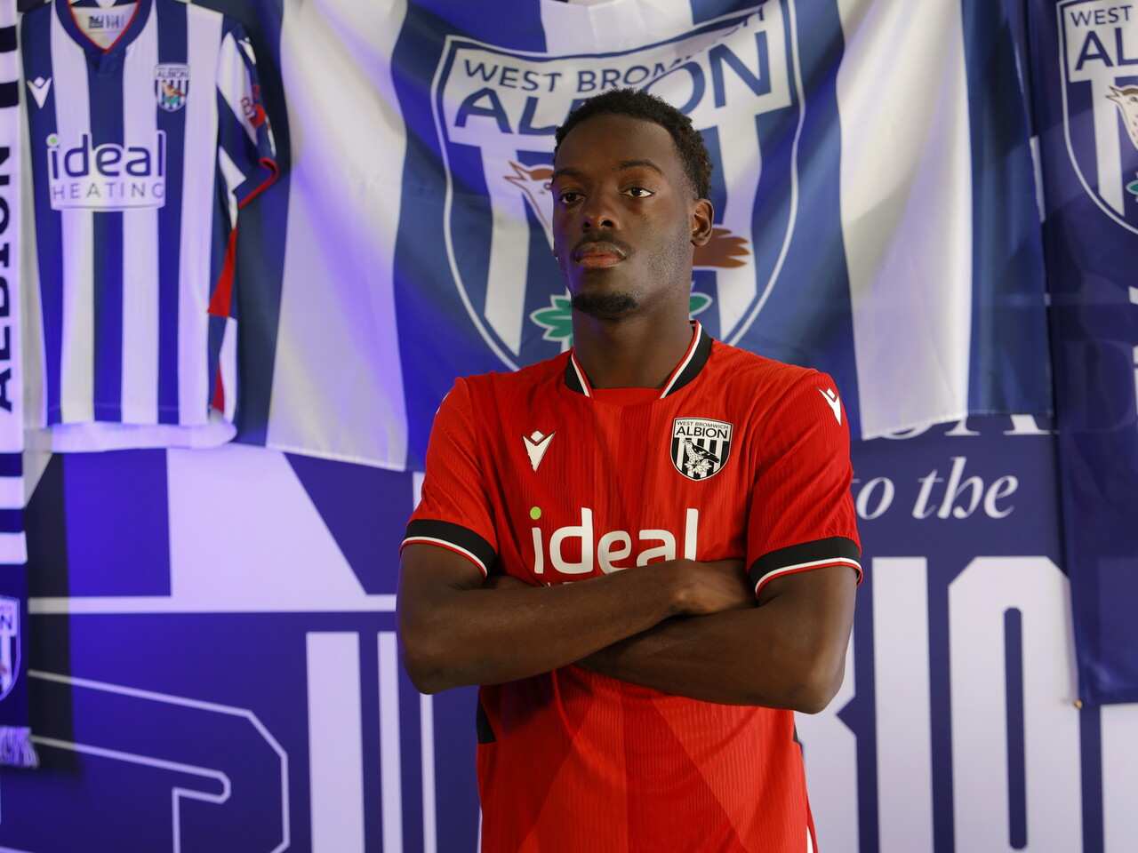 Rabby Nzingoula poses in front of a creative background in the away shirt