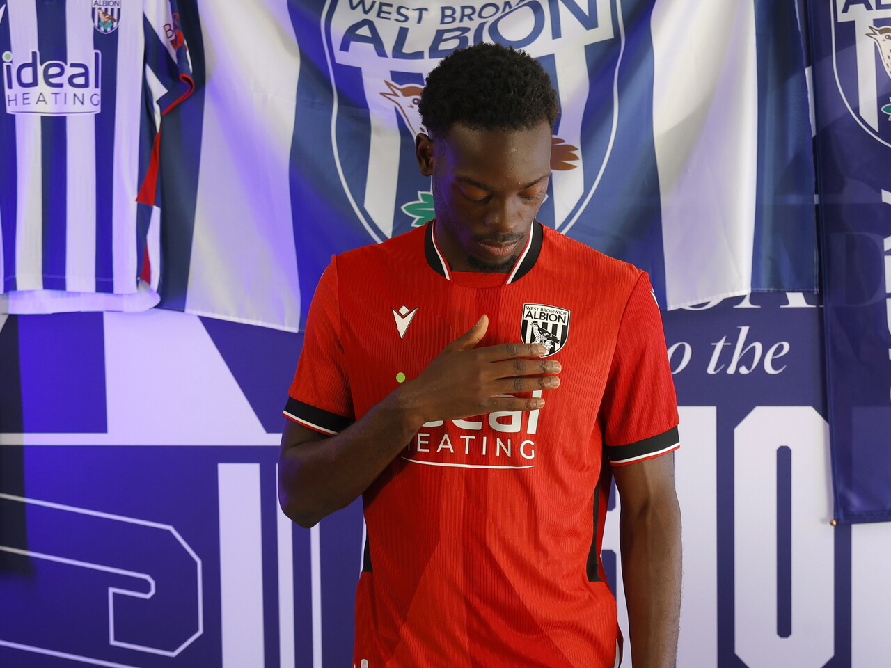 Rabby Nzingoula poses in front of a creative background in the away shirt