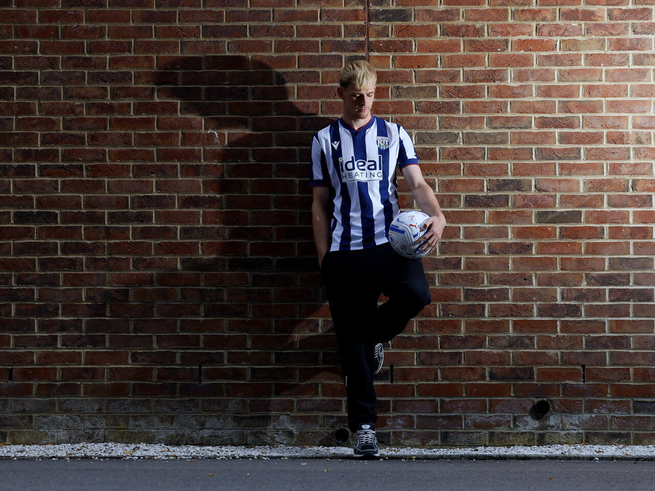 Toby Collyer poses against a brick wall with a ball in his left hand