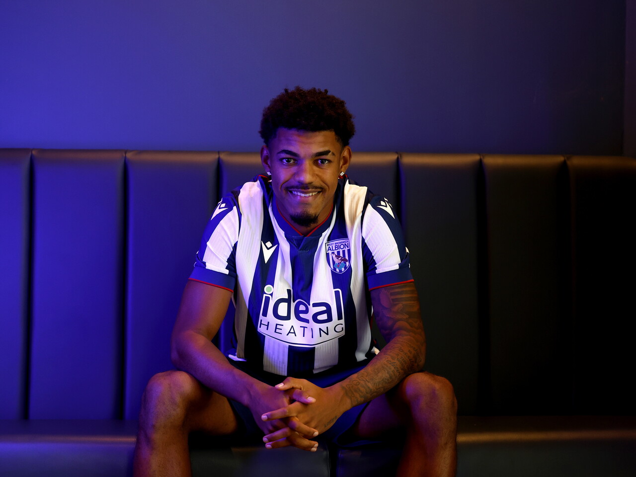 Kareem Tunde smiling at the camera while sat in a home WBA shirt