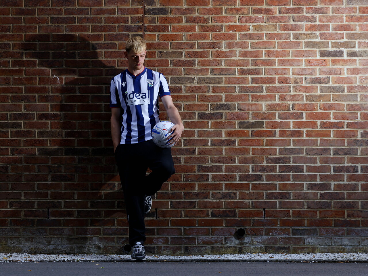 Toby Collyer poses against a brick wall with a ball in his left hand
