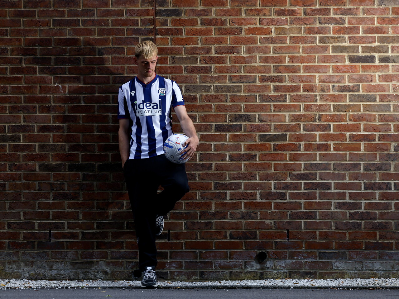 Toby Collyer poses against a brick wall with a ball in his left hand