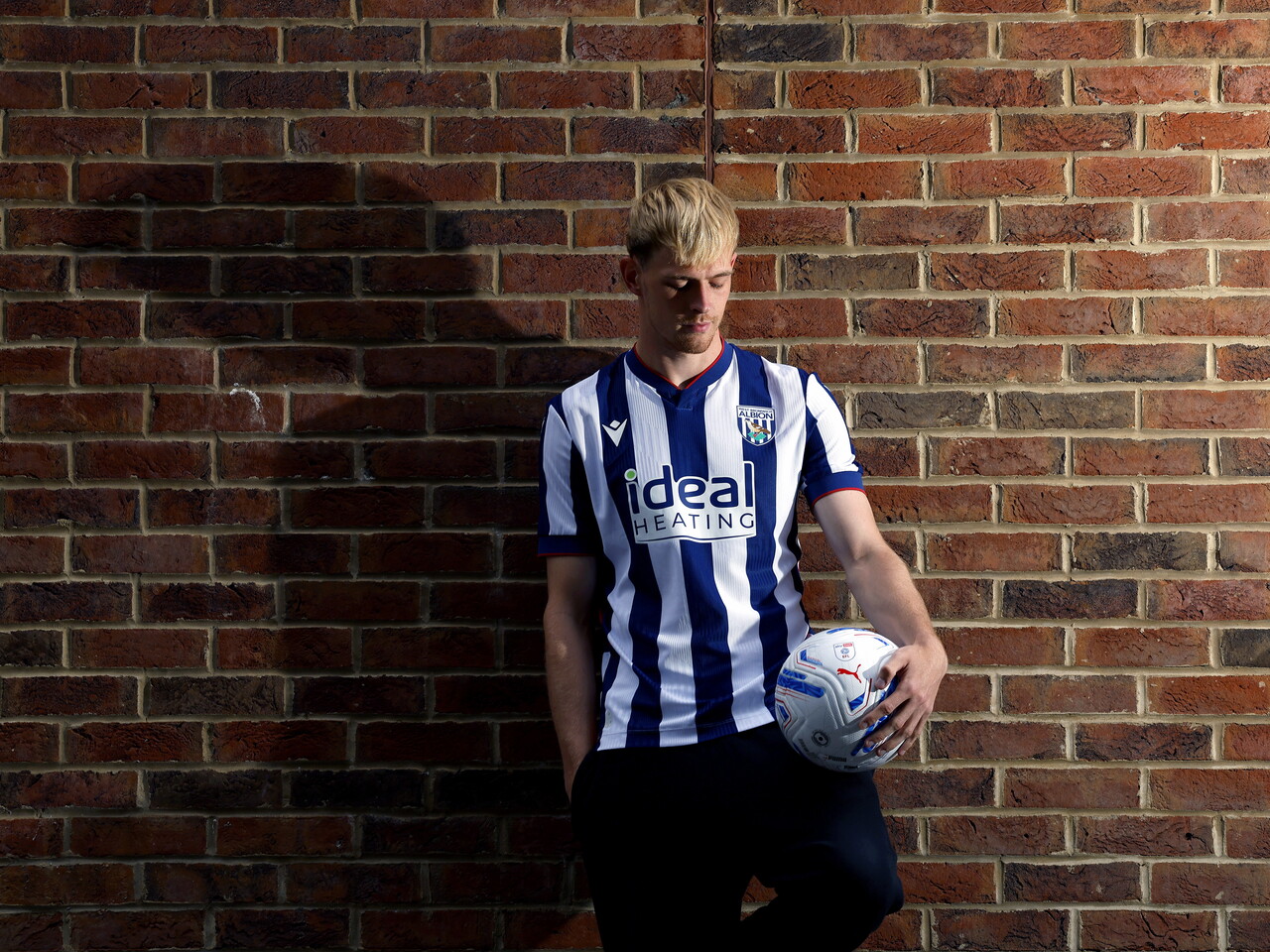 Toby Collyer poses against a brick wall with a ball in his left hand