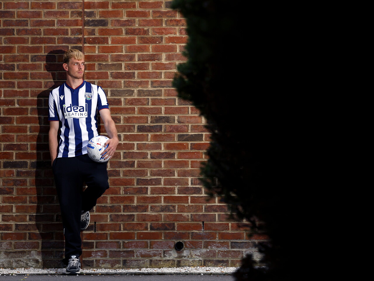 Toby Collyer poses against a brick wall with a ball in his left hand