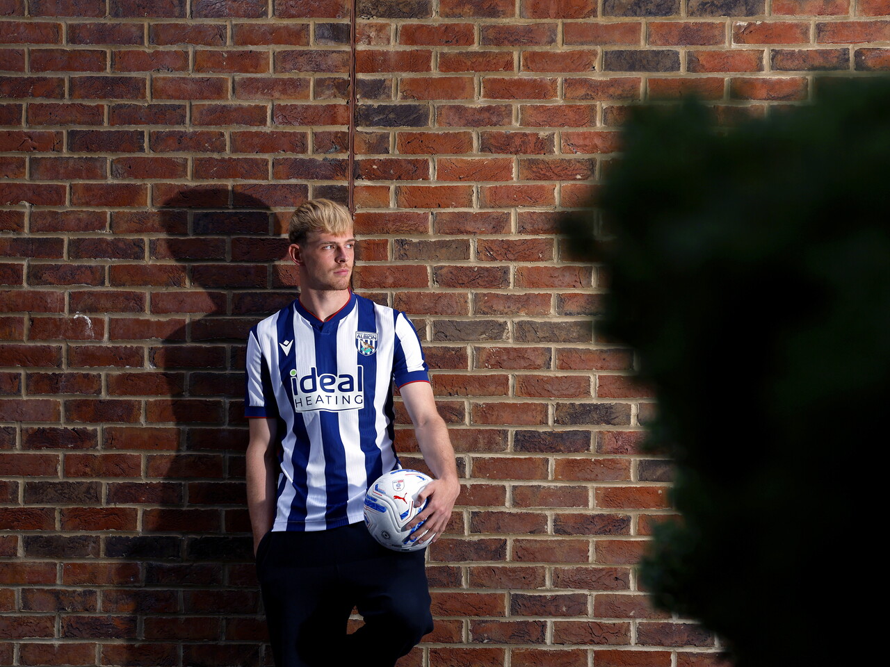 Toby Collyer poses against a brick wall with a ball in his left hand