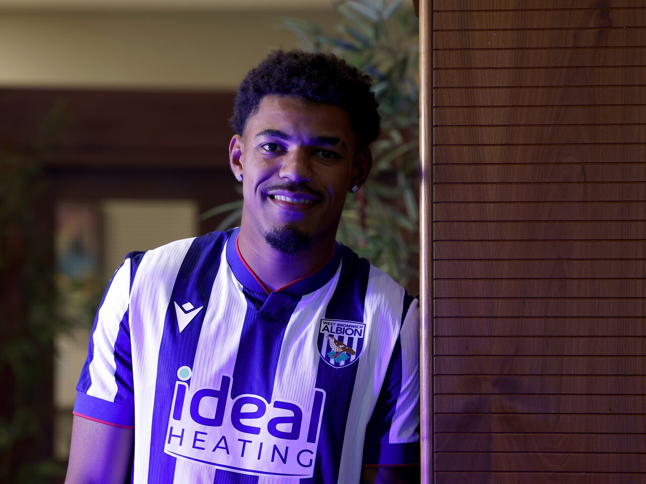 Kareem Tunde smiling at the camera while standing in a home WBA shirt