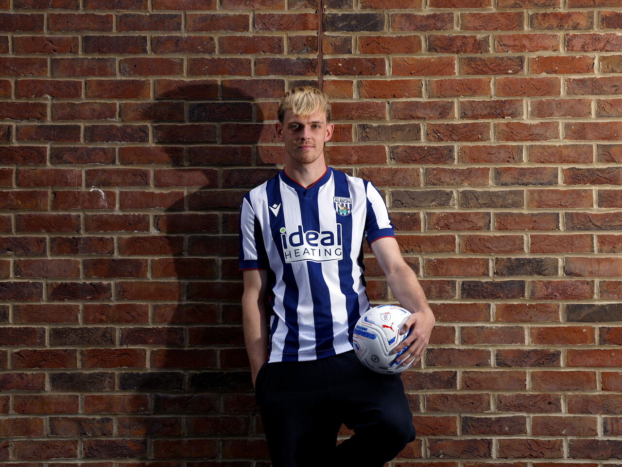 Toby Collyer poses against a brick wall with a ball in his left hand
