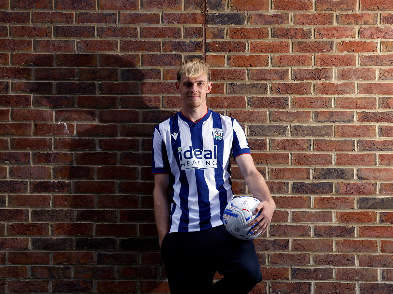 Toby Collyer poses against a brick wall with a ball in his left hand