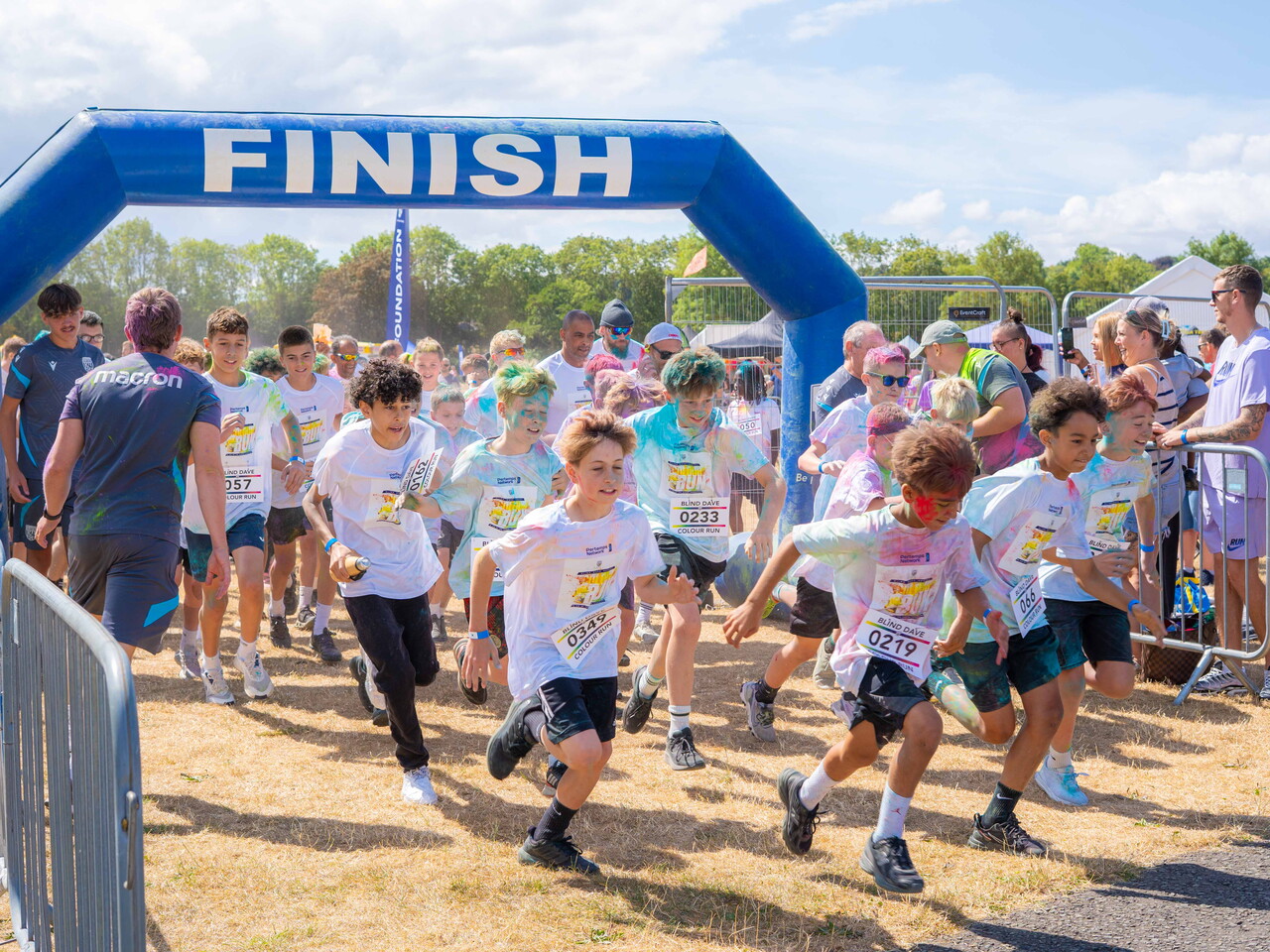 Participants run through a start line arch at a colour run event.