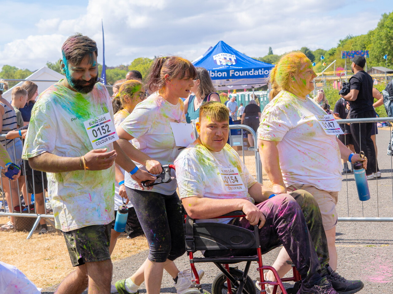 A participant in a wheelchair and other participants walking through the start line.