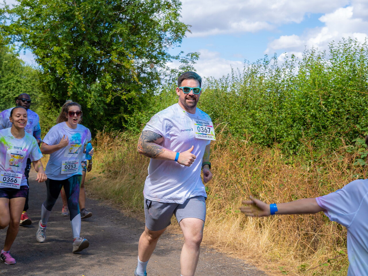 A small group of participants runs along the course surrounded by trees and greenery.