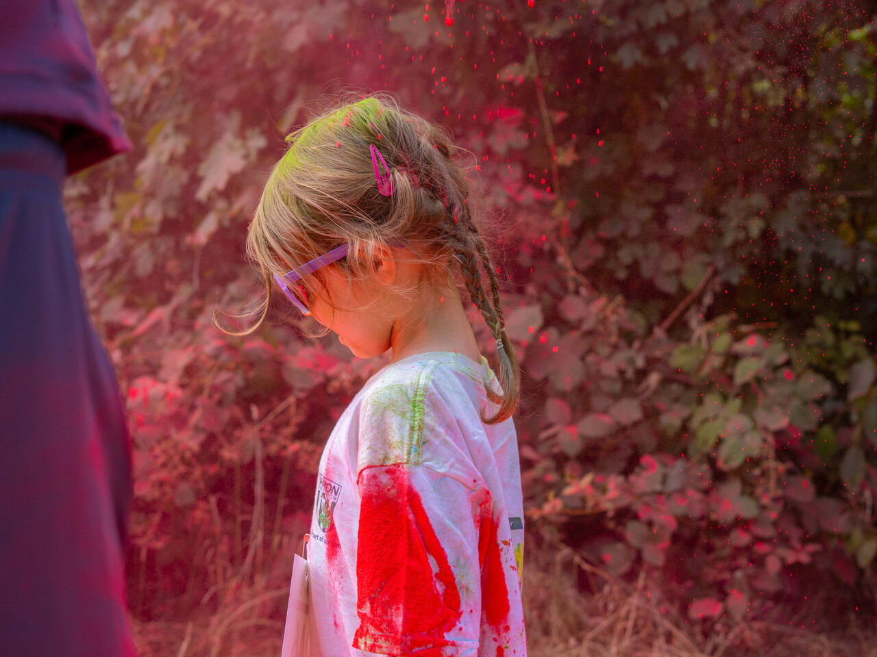 A child participant covered in pink powder walks along the route.