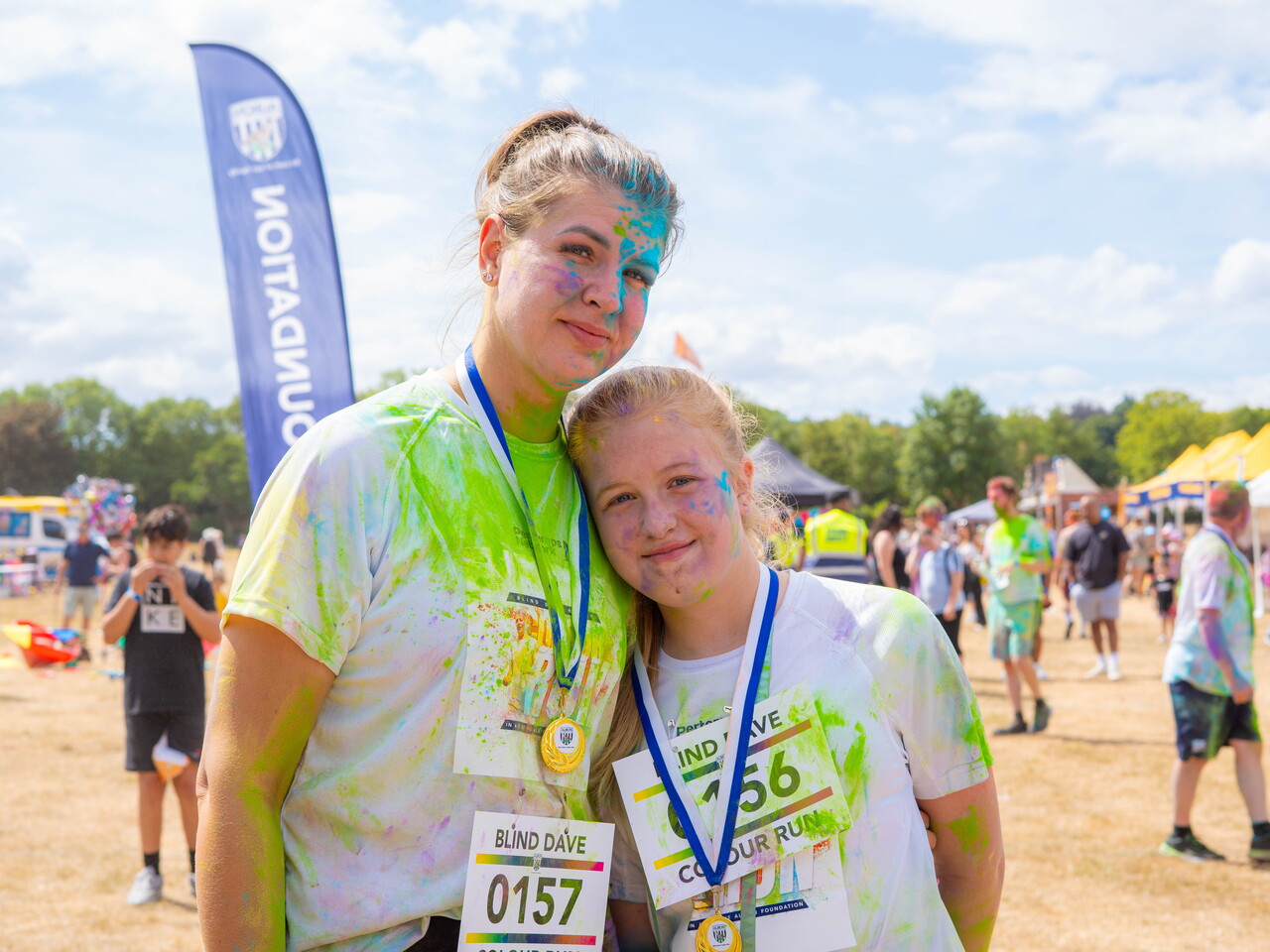 Participant posing after the Blind Dave Colour Run, wearing a finisher medal.