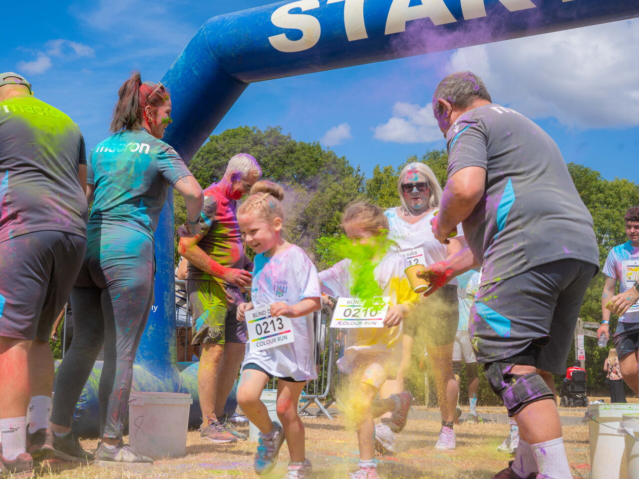 Participants and staff interacting and throwing paint near the event finish area.