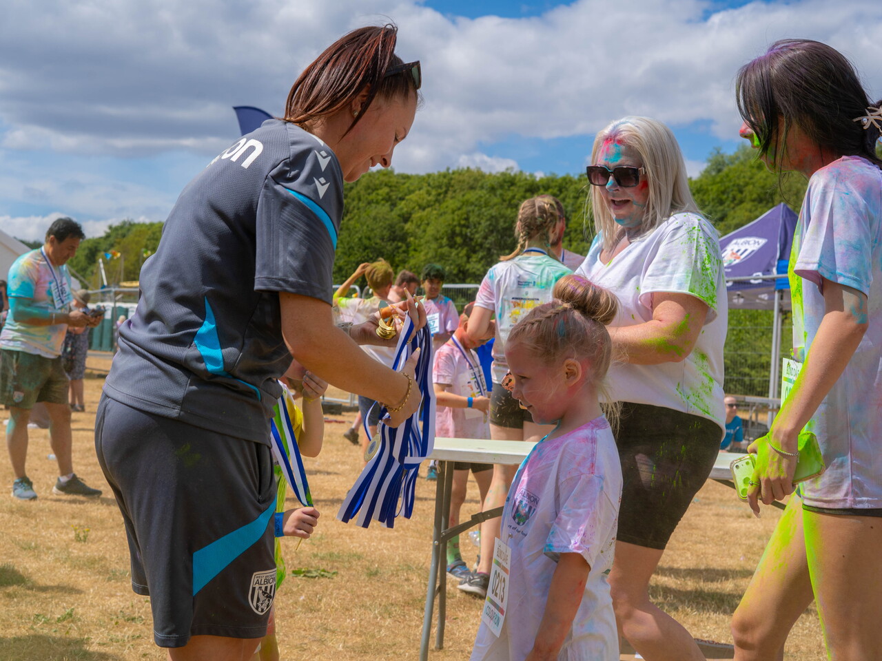Staff member assisting young participants with medal at the finish area.