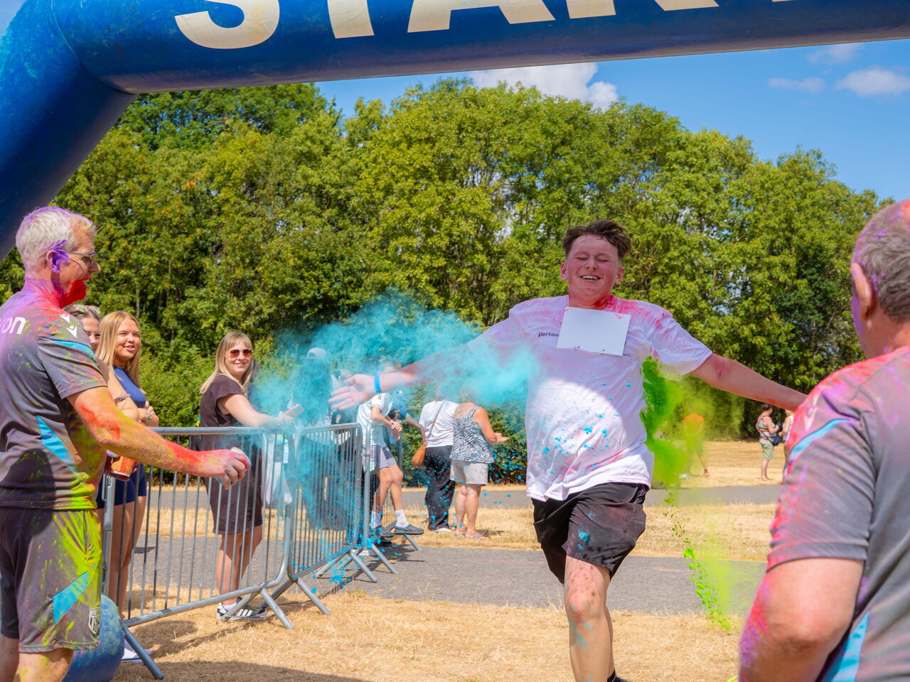 Participant running through coloured powder near the FINISH arch.