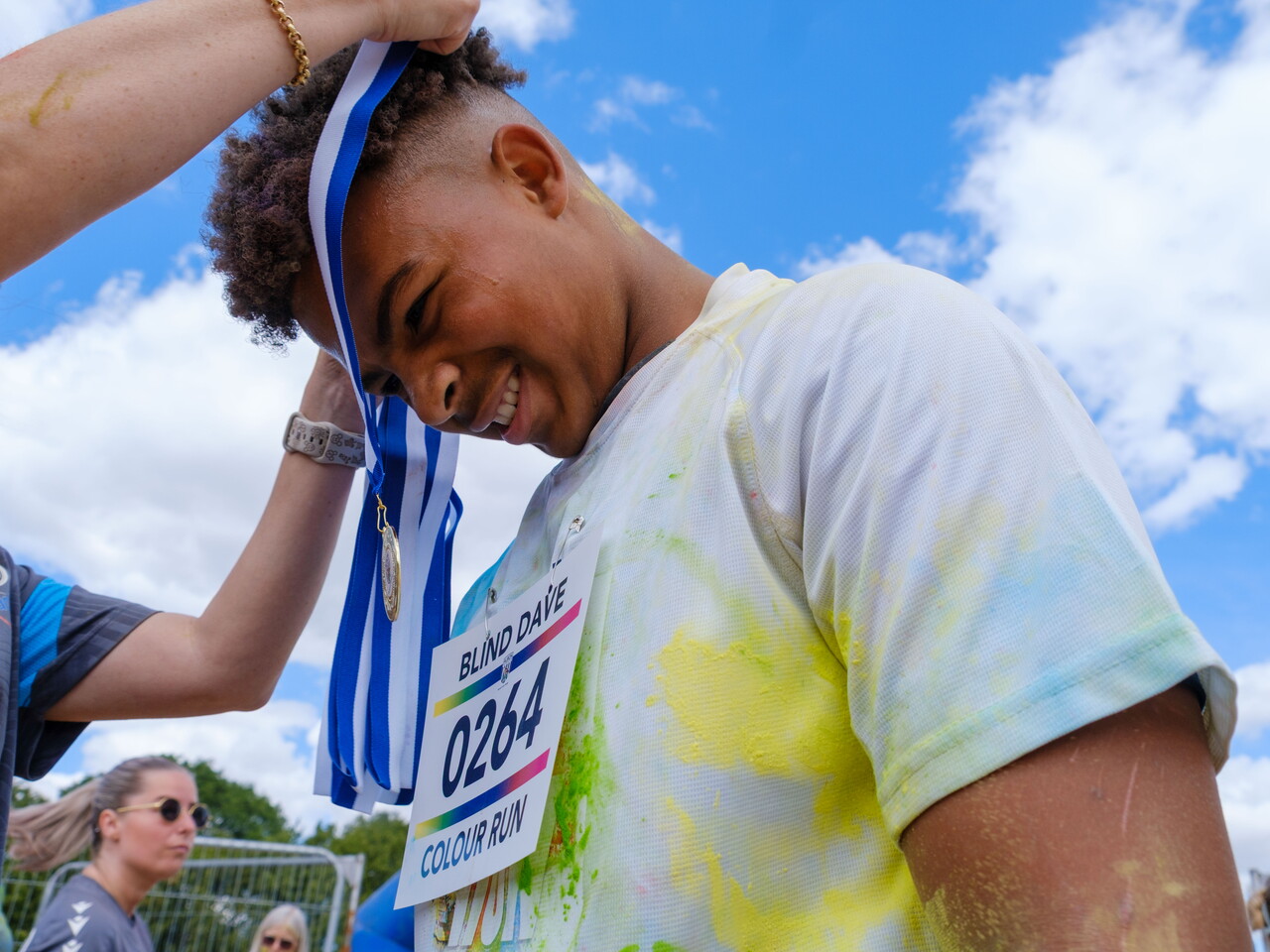 Staff member placing a medal around a participant's neck.