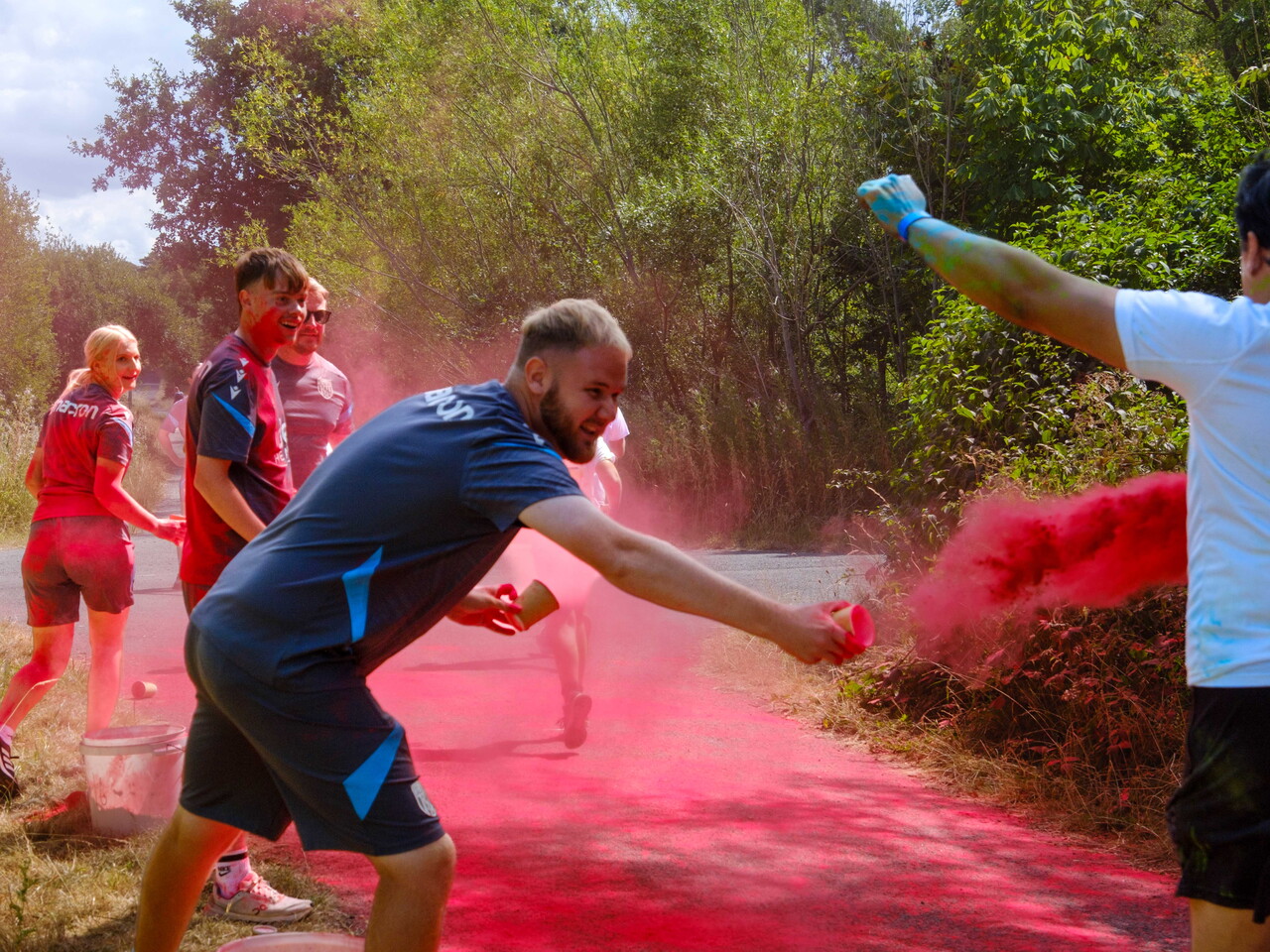 A participant runs through a cloud of pink color powder.