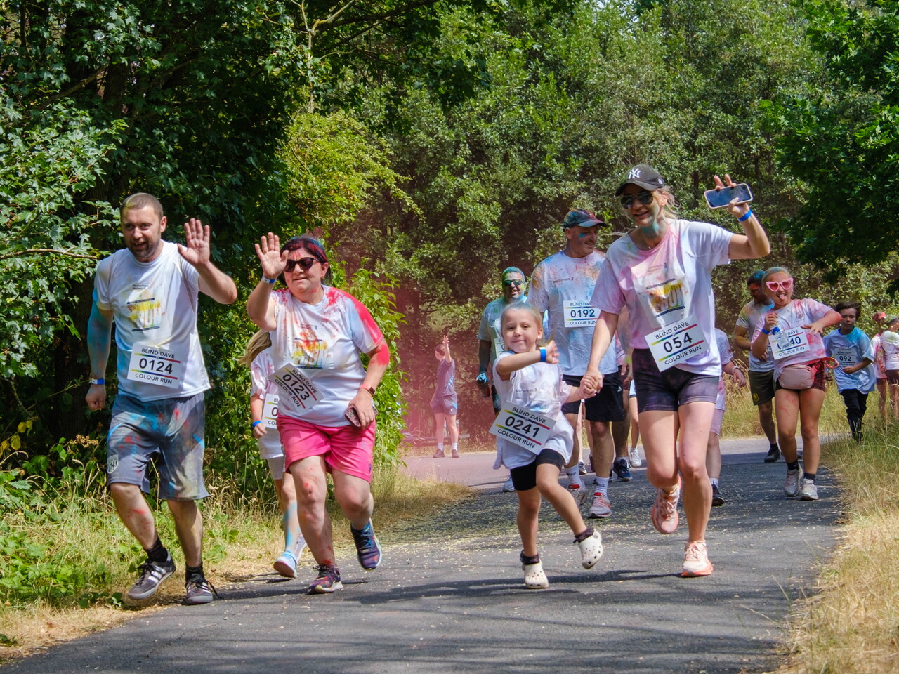 A group of participants walks and runs along a shaded path.