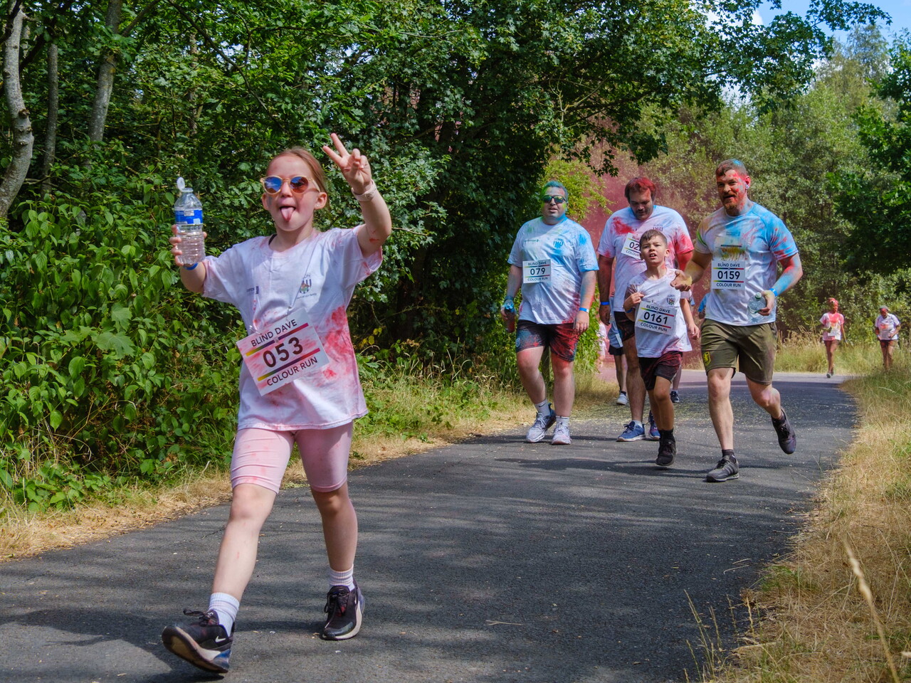 A participant waves while walking ahead of other participants on the course.