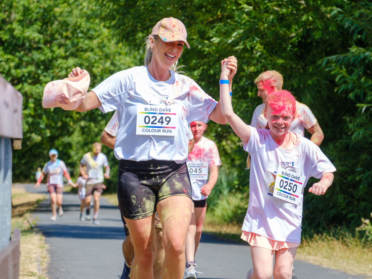 Two participants covered in color powder run side by side.