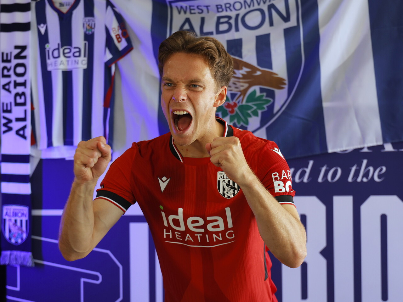 Felix Horn Myhre celebrating towards the camera in the red away kit in front of WBA branding 