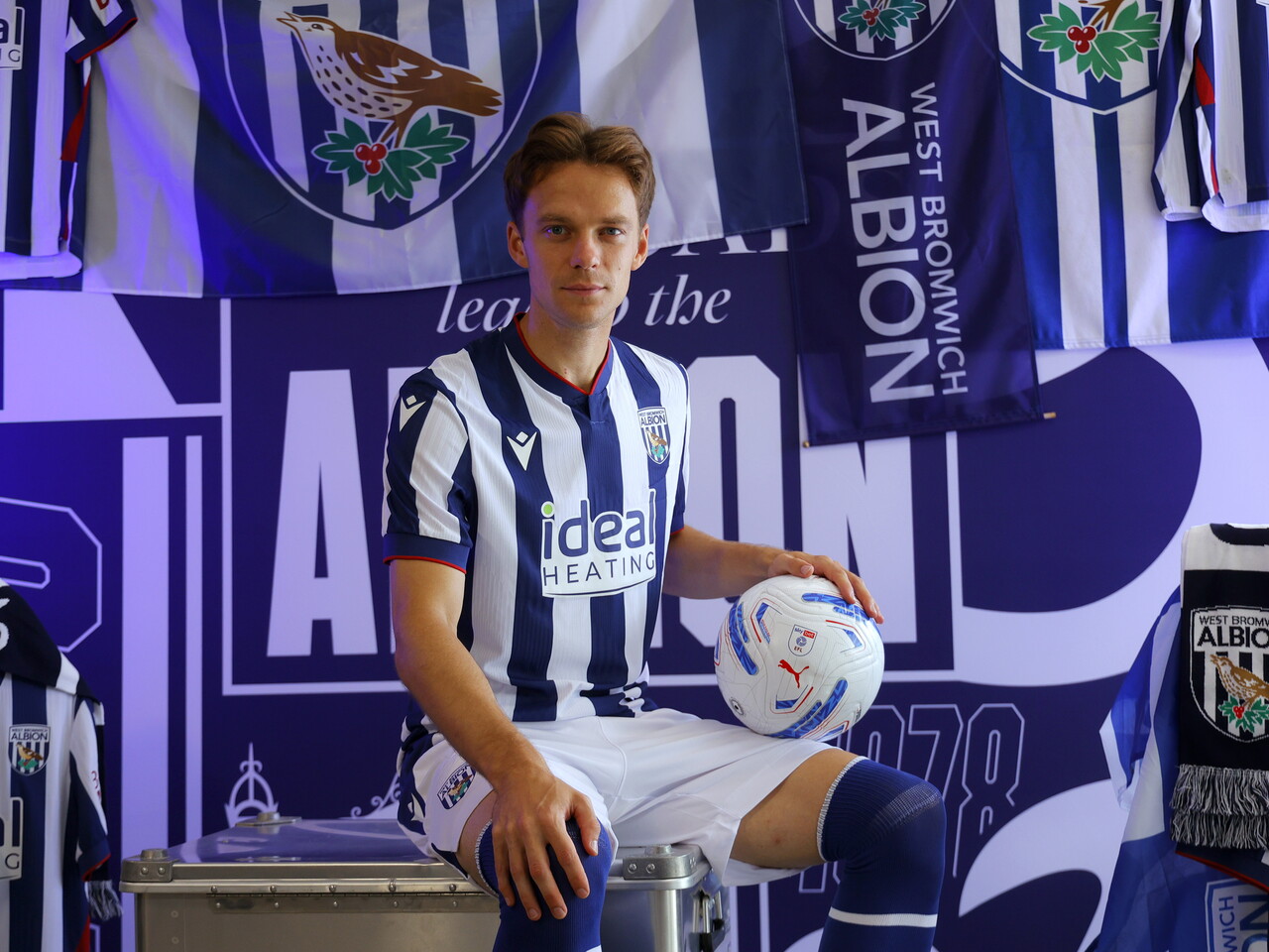 Felix Horn Myhre looking towards the camera while sat in the home kit in front of WBA branding