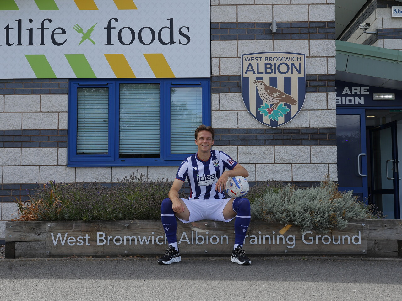 Felix Horn Myhre smiling at the camera while sat in the home kit outside the training ground
