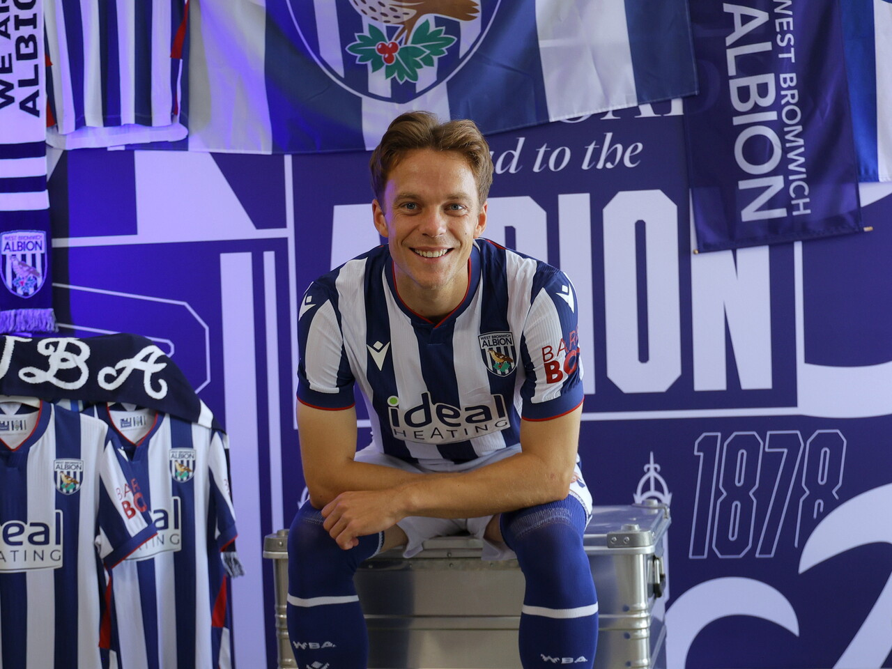 Felix Horn Myhre looking towards the camera while sat in the home kit in front of WBA branding